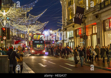 Massen von Weihnachtseinkäufern, die an Weihnachten in London, Großbritannien, entlang einer geschäftigen Regent Street spazieren Stockfoto