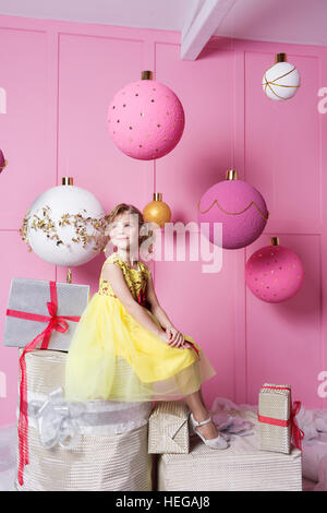 Hübsches Mädchen Kind 6 Jahre alt in einem gelben Kleid. Baby in Rosenquarz Zimmer dekoriert Urlaub. Stockfoto