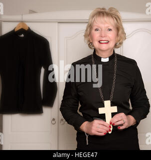 Reife Frau Priester hält ein hölzernes Kreuz Stockfoto