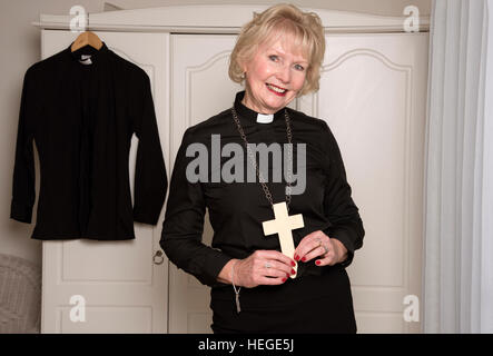 Reife Frau Priester hält ein hölzernes Kreuz Stockfoto