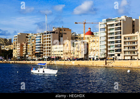 Yacht vor Anker in Sliema Creek, Valletta, mit Hotels und Kirche hinter. Stockfoto