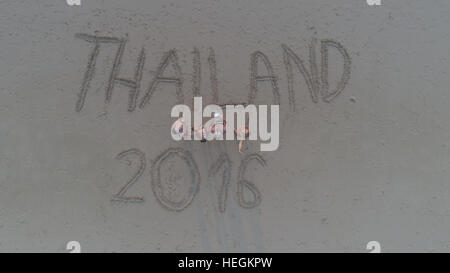Ansicht von oben Foto von Menschen stehen am tropischen Strand mit 'Thailand 2016"in Sand geschrieben. Menschen im Urlaub die Drohne Uo betrachten und winken. TR Stockfoto