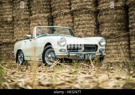 Creme MG Midget parkten vor Heu Bails Front auf. Stockfoto