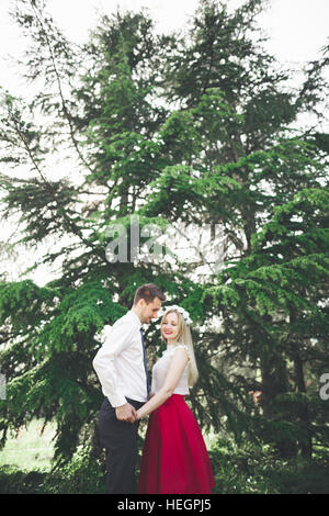 Stilvolle schöne glückliche Hochzeit paar küssen und umarmen im Botanischen Garten Stockfoto