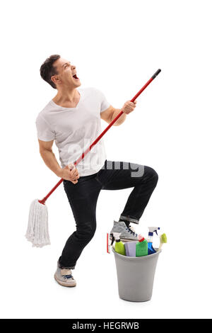 In voller Länge Portrait eines jungen Mannes, der vorgibt, Gitarre zu spielen, auf einem Mopp isoliert auf weißem Hintergrund Stockfoto
