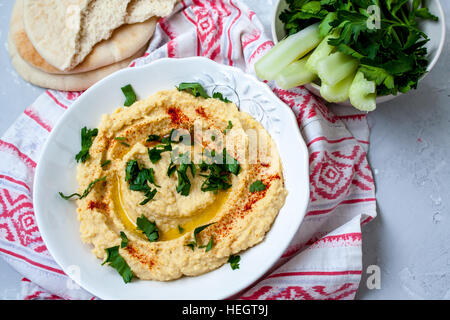 Startseite klassische Hummus mit Sellerie, Pita. Blick oben auf grauem Beton Hintergrund. Vegan Food-Konzept. Stockfoto
