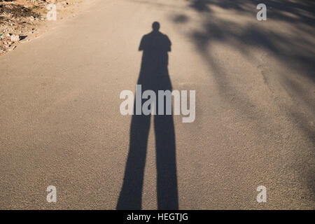 lange Schatten eines Mannes die Selfie auf der Straße in Indien Stockfoto