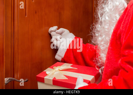 Santa Claus Übergabe Geschenkbox und klopfen die Tür Stockfoto