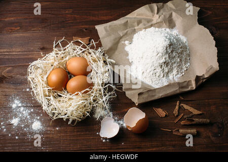 braunen Eiern, Mehl und Zimt auf einem dunklen Holztisch Stockfoto