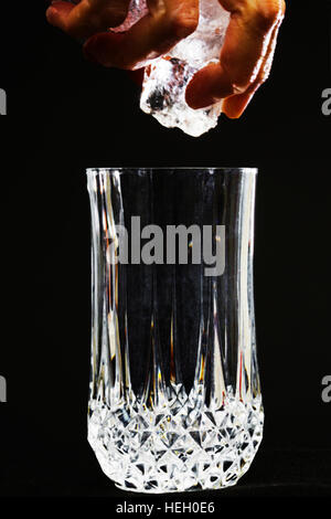 Hand Eis in ein Glas fallen. Stockfoto