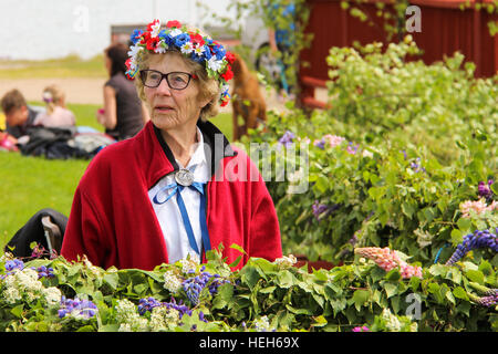 Eine schwedische Seniorin mit einer Blume KRONE Mittsommerfest am Läcko Slott in Schweden vorbereiten Stockfoto