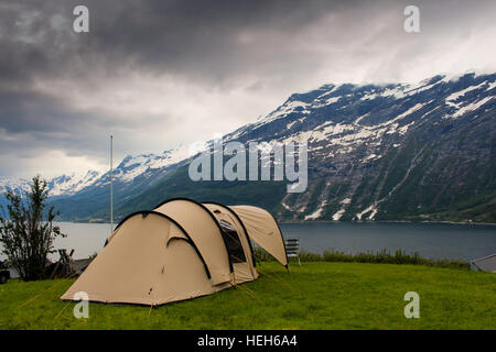 Zelten an einem norwegischen Fjord mit dunklen Wolken und Schnee-bedeckten Bergen im Hintergrund Stockfoto