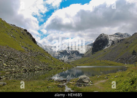 Typische Schweizer Alpine Landschaft mit schneebedeckten Bergen im Hintergrund und einem kristallklaren See im Vordergrund Stockfoto