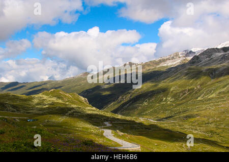 Sehen Sie sich auf ein Schweizer Alpenlandschaft mit einer kurvenreichen Straße und bewölktem Himmel Stockfoto