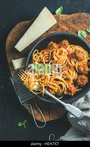Italienische Pasta-Essen. Spaghetti mit Meatballas, Basilikum und Parmesan in schwarze Platte über rustikale Holz dunkel, Draufsicht, Slow Food Gedanke Stockfoto