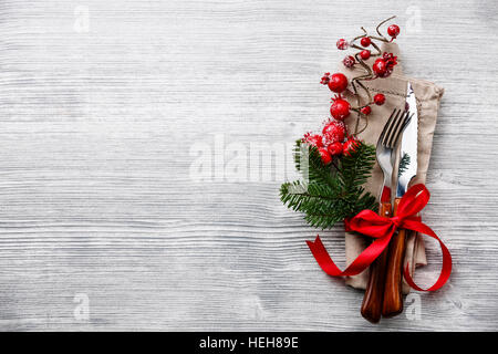Gabel und Messer Set mit Serviette, Weihnachten Tanne Zweig, roten Beeren und Band auf grauem Holz Hintergrund textfreiraum Tisch Stockfoto