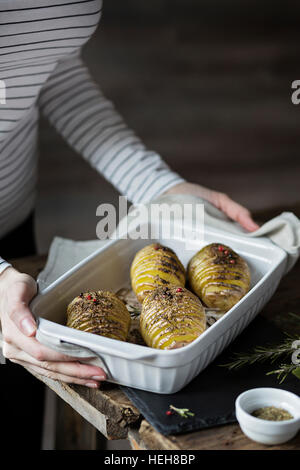 Frau mit gerösteten Hasselback Kartoffeln Stockfoto