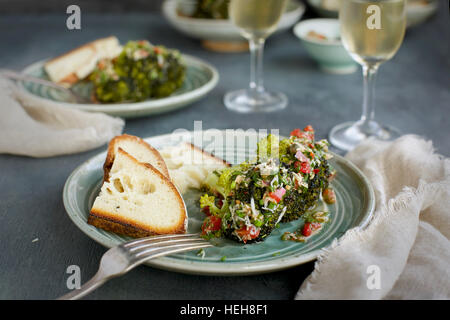 Mangold-Brokkoli mit Tomaten italienische Stil Salsa Verde serviert mit Brot und Weißwein. Davonsausen aus Draufsicht auf eine grün/grauen Hintergrund. Stockfoto