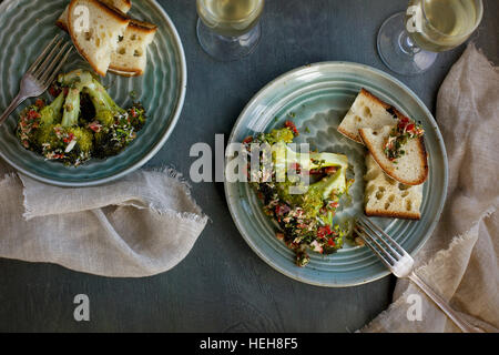 Mangold-Brokkoli mit Tomaten italienische Stil Salsa Verde serviert mit Brot und Weißwein. Davonsausen aus Draufsicht auf eine grün/grauen Hintergrund. Stockfoto