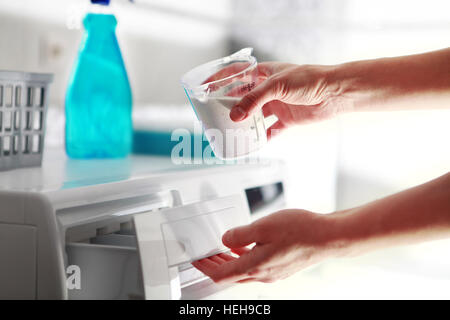 Hände der Frau, das Waschmittel in der Waschmaschine füllt Stockfoto