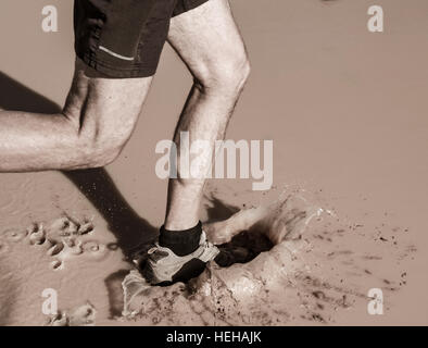 Mann läuft durch schlammige Pfütze. Stockfoto