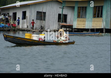 Frau trägt ein frachtboot. Fischerdorf auf dem Wasser. Mengkabong Fluss, Kota Kinabalu, Sabah, Borneo, Malaysia. 22 Jun 2012 Stockfoto