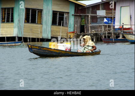 Frau trägt ein frachtboot. Fischerdorf auf dem Wasser. Mengkabong Fluss, Kota Kinabalu, Sabah, Borneo, Malaysia. 22 Jun 2012 Stockfoto