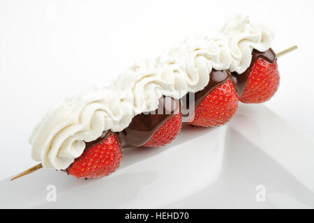 Aufgespießt Schokolade beschichtete Erdbeeren mit Schlagsahne Stockfoto