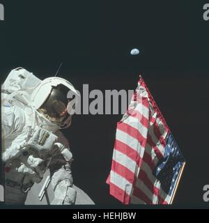 NASA Apollo 17 Mondlandung Mission Astronaut Harrison Schmitt steht neben einer amerikanischen Flagge während der ersten Extravehicular Tätigkeit auf der Mondoberfläche 11. Dezember 1972 auf dem Mond. Astronaut Gene Cernan ersichtlich in der Reflexion visieren. Stockfoto