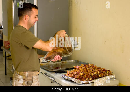 US Marine Corps, Capt Chris Carter, von Overland Park, Kansas, der 1. Panzer-Bataillon, 1. Marineabteilung, Sitz in Twentynine Palms, Kalifornien, bereitet shish Kababs, mit Soldaten der irakischen Armee und irakische Polizisten während Weihnachtsessen am 24. Dezember 2008, im Stadtteil Al Hayyaniah, Basra, Irak zu teilen. Weihnachten-Silvester-Dinner in Basra 140771 Stockfoto