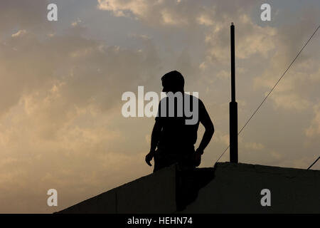 US Marine Corps, Capt Chris Carter, von Overland Park, Kansas, der 1. Panzer-Bataillon, 1. Marineabteilung, Sitz in Twentynine Palms, Kalifornien, behebt eine Antenne auf dem Dach der 26. Brigade irakische Armee darauf aufbauend, 24. Dezember 2008, im Stadtteil Al-Hayyaniah, Basra, Irak. Auf dem Dach-Antenne-Reparatur 140770 Stockfoto