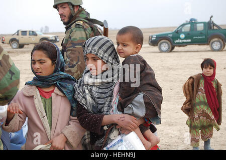 Ein junge afghanische Mädchen hält ein Kind schaut zu, wie ein anderes Mädchen ihre Hand streckt markiert werden, bevor sie durch die Leitung zu decken und Kleidung während einer jüngsten humanitären Hilfsmission in Nordafghanistan geht. Die HA-Mission in das Dorf Yakku Tut 27. Dezember 2008, wurde geplant, organisiert und durchgeführt von der afghanischen Nationalarmee und die afghanische Polizei unter der Mentorenschaft von afghanischen regionale Integration Befehl Sicherheit - Nord, kombiniert Joint Task Force Phoenix VIII, 33. Infantry Brigade Combat Team. Afghanische Armee unterstützen Polizei nördlichen afghanischen Dorf humanitäre assis Stockfoto