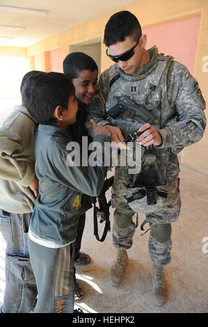 Capt Agustin Dominguez, gebürtig aus Miami, Florida, Brände unterstützen Offizier zugewiesen Headquarters und Headquarters Company, 2. Bataillon, 505. Fallschirm-Infanterie-Regiment, 3rd Brigade Combat Team, 82nd Airborne Division, Multi-National Division-Bagdad zeigt einige irakische Kinder seine Kamerabildschirm nach der Einnahme ein Bild von ihnen während einer humanitären Fahrt 4 Februar an einer Schule im Stadtteil neue Bagdad Osten Bagdads. Fallschirmjäger zugewiesen zum 2. Bataillon, 505. Fallschirm-Infanterie-Regiment, eine Partnerschaft 3rd Brigade Combat Team, 82nd Airborne Division, Multi-National Division-Bagdad mit natio Stockfoto