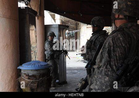 US Army Spc Matthew Glasscock (links), ein Mitglied der US Armee Oberst Timothy McGuire persönliche Sicherheit Detail, 3rd Brigade Combat Team, 82nd Airborne Division, bietet Sicherheit aus einer überdachten Position neben einer Gasse, wo irakische Soldaten Handfeuerwaffen mit bewaffneten, im Stadtteil Al-Fadhel östlichen Bagdad, Irak, am 29. März 2009 austauschen. Patrouille in Bagdad 169448 Stockfoto