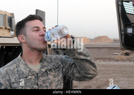 Staff Sgt Omar Colom, ein LKW-Kommandeur für Staff Sgt Jessel Rojas Combat Escort Team, trinkt Wasser nach Abschluss einer der vielen langen Touren auf Mission im Irak. LKW-Kommandanten, es sei denn, eine zusätzliche Passagier, sind verantwortlich für zwei Soldaten: ein Fahrer und ein Schütze. CET - A Escort Kampfmannschaft mit 1. Bataillon, Infanterie-Regiment 124. weitergeht Nachschubkonvois für Sicherheit im Irak 286940 Stockfoto