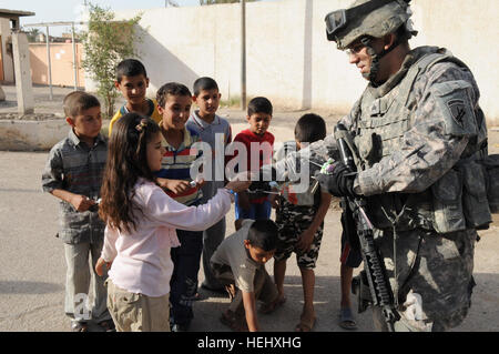 Sgt. Bryan Patenge, von Phoenix, Arizona, 401. Civil Affairs Bataillon, zugewiesen verteilt Süßigkeiten für Kinder während einer humanitären Mission 19 Mai in der Stadt Idrissi befindet sich im Stadtteil Rusafa von östlichen Bagdad. Zivilrechtliche Angelegenheiten Soldaten und Fallschirmjäger zugewiesen Headquarters und Headquarters Troop, 5. Staffel, 73. Kavallerie-Regiment, 3rd Brigade Combat Team, 82nd Airborne Division, Multi-National Division-Bagdad, Fußball Ausrüstung und anderen Gütern ausgehändigt, um die Lebensqualität für Bürger in der Stadt zu verbessern. (US Armee-Foto von Spc Joshua W. Lowery) Fallschirmjäger d Stockfoto