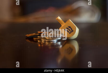 Aus Holz Dreidel ruht auf Haufen von Münzen Stockfoto