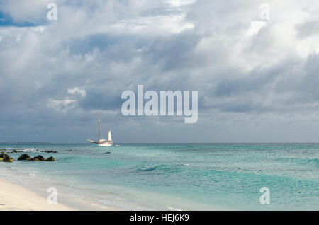 Bild zeigt ein großes Segelboot am Meer navigieren in Richtung Strand. Das Bild wurde aufgenommen von Arashi Beach, Aruba in der Karibik. Stockfoto