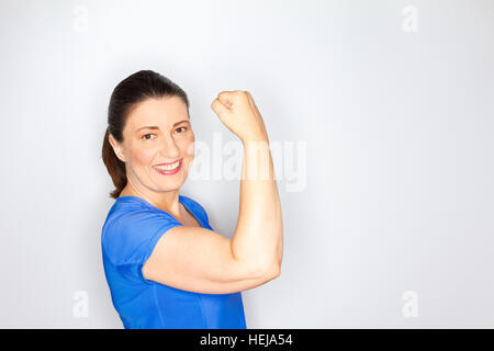 Woman in hell blau Sportoutfit zeigen ihre Bisceps Muskeln, hellem Hintergrund, Kopie oder Text Platz, Exemplar applying Stockfoto