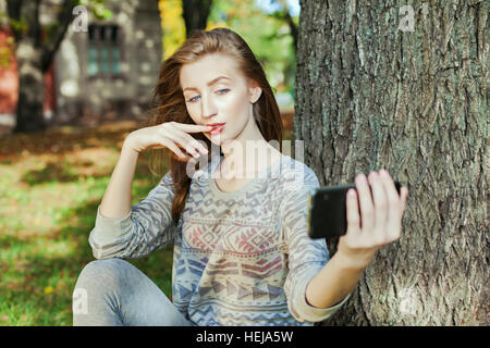 Schöne Mädchen mit blauen Augen macht Selfie im freien Stockfoto