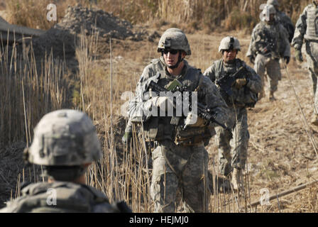 Sgt. Michael Benoit, Kavallerie scout Gruppenleiter von Monticello, Minn, zugewiesenen Truppe C, 7. Staffel, 10. Kavallerie-Regiment, 1st Brigade Combat Team, 4. US-Infanteriedivision, Multi-National Division - Bagdad, führt Soldaten aus den 752nd Explosive Ordnance Company, Mitgliedern des 1. Platoon, Jan. 28, in einem Feld am Stadtrand von Abu T'shir Gemeinschaft im Bezirk Rashid Süden Bagdads. Die Soldaten der Brigade "Raider" erhöht ihre laufende Sicherheits-Operationen in der letzten Januarwoche zur Vorbereitung der kommenden irakische Provinzwahlen, geplant für den 31. Januar. Stockfoto