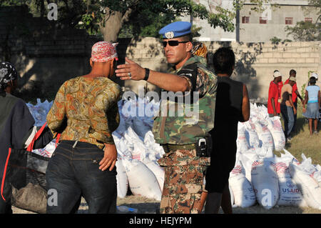 Jordanischen UN Militär Polizist leitet haitianischen Bürger sammeln Säcke Reis einen Verteilungspunkt World Food Program in Port-au-Prince, Haiti am 6. Febr. Fallschirmjäger zugewiesen Headquarters und Headquarters Company, 2nd Brigade Combat Team, 82nd Airborne Division unterstützt die UN mit Sicherheit während der Tropfen. (US Armee-Foto von Pfc. Kissta M. Feldner, 2BCT, 82. Abn. Div. PAO) Jordanier Secure World Food Programm Verteilungspunkt 248939 Stockfoto