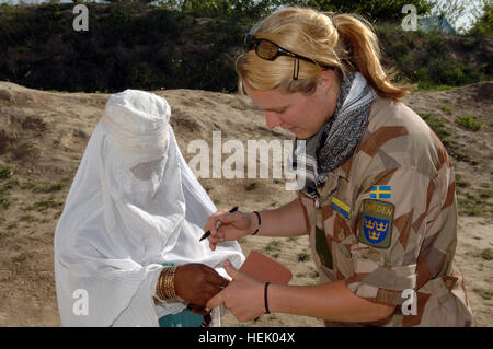 Schwedische Nationalarmee 1st Lt. Elisabeth Alm, militärische Beobachter Team Liaison Officer, markiert die Hand einer Frau in Reihenfolge für sie medizinischen Hilfe von Gesundheitsdienstleister bei medizinischen zivile Hilfe Programm (MEDCAP) im Dorf Stin, der Provinz Balkh, Afghanistan am 4. April 2006 erhalten. Diese MEDCAP gliedert sich durch kombiniert Joint Special Operation Task Force - Afghanistan für Männer, Frauen und Kinder in der Provinz Balkh. (Foto: U.S. Army Spc. Michael Zuk) (Freigegeben) Schwedische militärische Beobachter Team Verbindungsoffizier in Afghanistan 2006 Stockfoto