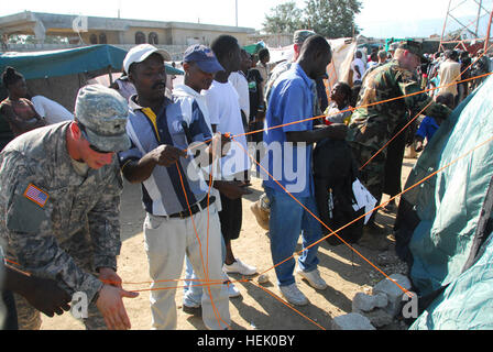 PORT-AU-PRINCE, Haiti (20. Februar 2010) - Mitglied ein Informationen-Support-Team von U.S. Army Special Operations Command, hilft mehrere haitianische Männer während einer Verteilung humanitärer Hilfe, 20 Februar ein neues Zelt in einem Hubraum-Camp in Port-au-Prince einrichten. Das zivile Angelegenheiten-Team führte den Betrieb gemeinsam mit der 82. US-Luftlandedivision und Shelter Box, eine Nichtregierungsorganisation, die fast 100 Zelte für das Camp zur Verfügung gestellt. (US Armee-Foto von Sgt. Tony Hawkins, USASOC PAO) Haitianer erhalten neue Zelte 253341 Stockfoto