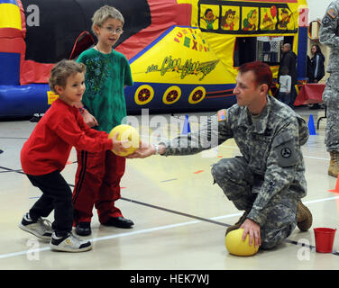 Sgt. 1. Klasse Andrew England, mit dem 3. Sustainment Befehl (Expeditionary), übergibt eine Bowlingkugel Pierce Elementary School Student an der Schule Winterfestival Dez. 2. England und etwa 24 anderen Soldaten aus der 3. ESC freiwillig ihre Zeit gerne mit dem Schulfest. Handlangern zurückgeben an Pierce elementare Winter Fest 347108 Stockfoto