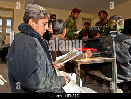 Ein afghanischer Junge liest aus einem Comic-Buch, die ihm gegeben durch afghanische Soldaten mit 3. Commando Kandak Sayeed Shied Bacha Schule, 9. Dezember 2010, in der Provinz Kandahar, Afghanistan. Die Kommandos, unterstützt von US-Soldaten mit Special Operations Task Force - South, verteilt auch Jacken, Rucksack und andere Versorgungsgüter für die Schüler. (US Armee-Foto von Spc. Daniel P. Shook / Special Operations Taskforce - Süd) (Freigegeben). Afghanische Commandos, uns Soldaten erreichen, um Gemeinschaft 348576 Stockfoto