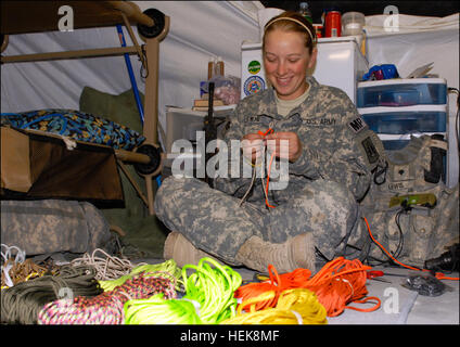 SPC. Amber Lewis, Militär Polizist zugewiesen 372nd Military Police Company, 504th Military Police Battalion, derzeit angeschlossen, 1st Brigade Combat Team, 4. US-Infanteriedivision aus Camp Nathan Smith, Afghanistan, arbeitet an einem 550-Kordel-Armband 17 Jan. für ein Paket von handgefertigten waren, die sie an eine Gruppe von Schüler der 3. Klasse in Romney Elementary School in ihrer Heimatstadt Romney senden , W.VA Die 21 Jahre alte MP wurde angeregt, um beginnen Armbänder wieder nach Hause zu senden, nachdem er einen Brief von ihr 8 Jahre alten Neffen teilte ihr mit, dass er nie nehmen würde das Armband aus, dass sie gab Stockfoto