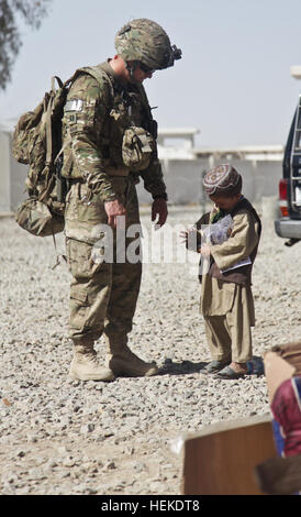 US Army Captain Rader gibt einem Afghanistan-jungen eine Markierung außerhalb der Kreisstadt in Spin Boldak City, Provinz Kandahar, Afghanistan, 18. September 2011. (Foto: U.S. Army Spc. Kristina Truluck) Expeditionary Frauenmannschaft, lokalen nationalen weibliche Gesundheitserziehung 110918-A-VB845-294 Stockfoto