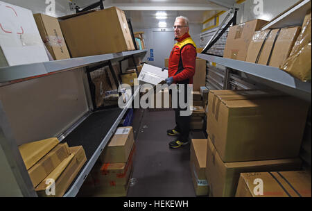 Die Paket-Zusteller Hans-Joachim Harnagel trägt eine Paket in seinem Post-Fahrzeug bei der DHL-Lieferung Basis Braunschweig, Deutschland, 21. Dezember 2016. Danach liefert Harnagel Päckchen und Pakete an die Empfänger während einer Reise durch die Innenstadt von Braunschweig. Foto: Holger Hollemann/dpa Stockfoto