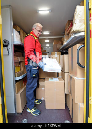 Die Paket-Zusteller Hans-Joachim Harnagel mit einem Paket in den Händen in seinem Lieferwagen während einer Lieferung runden Braunschweig, Deutschland, 21. Dezember 2016. Rund 280 Päckchen und Pakete liefern wir an ihre Empfänger während einer Reise durch die Innenstadt von Braunschweig. Foto: Holger Hollemann/dpa Stockfoto